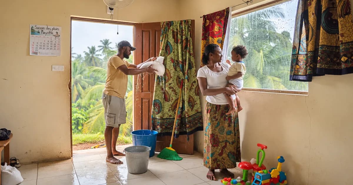 Famille à Mayotte préparant la maison pour la saison des pluies, avec seaux et balai