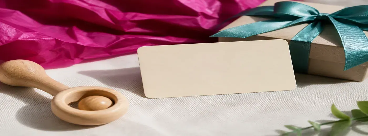 Carte cadeau posée près d’un hochet en bois et d’un petit paquet