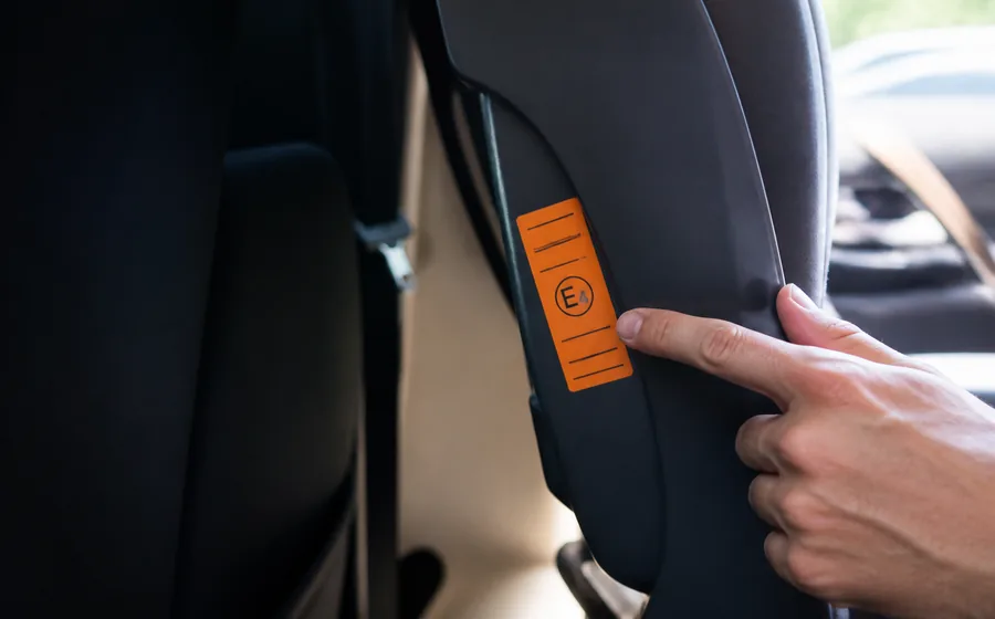 Étiquette d’homologation d’un siège auto, doigt d’adulte, habitacle clair