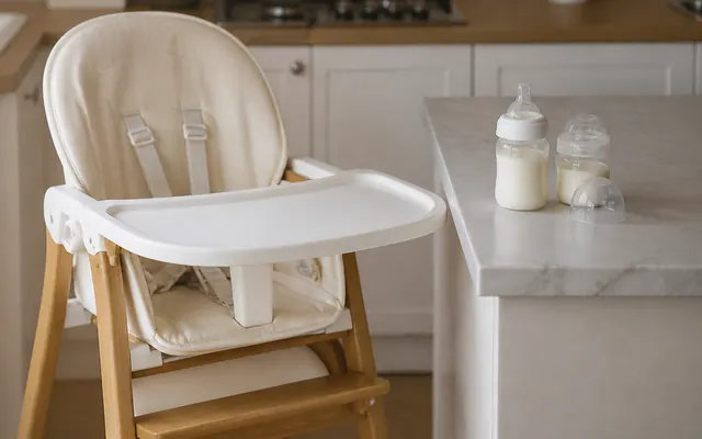 Chaise haute et biberons sur un plan de travail clair