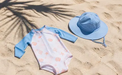 Combinaison anti-UV et chapeau posés sur du sable clair