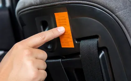 Étiquette d’homologation d’un siège auto, désignée du doigt