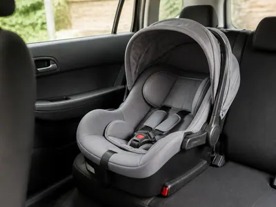 Siège auto bébé gris installé sur une banquette